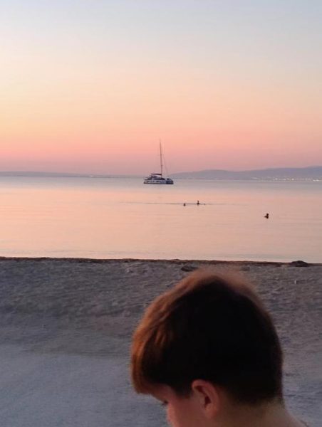 Atardecer romántico en la playa del Hotel Anemos con velero al fondo y aguas tranquilas en calma