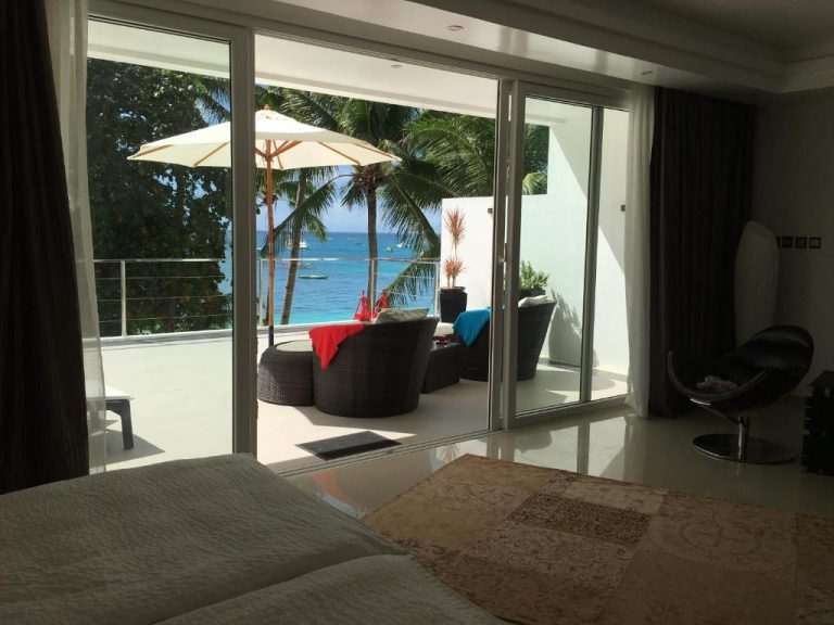 Habitación con terraza y vista al mar turquesa en Sundown Beach Studios con tumbonas y palmeras