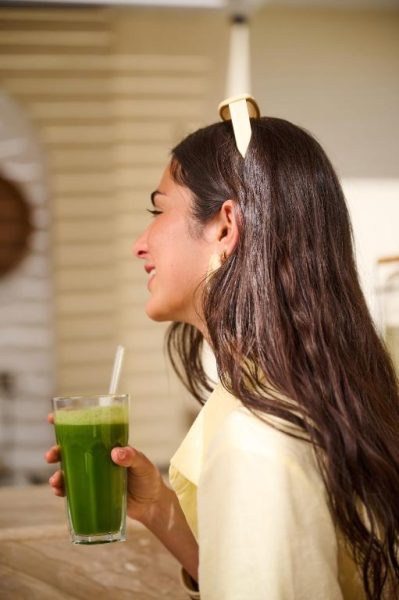 Mujer sosteniendo un vaso de zumo verde detox en TheLifeCo Sharm El Sheikh, experiencia wellness