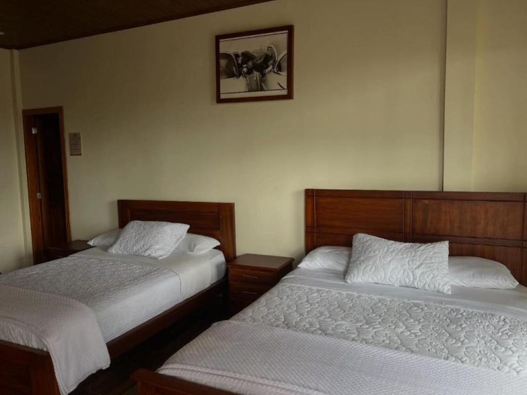 Habitación doble con dos camas y cabeceros de madera en el hotel La Quinta de Andrés