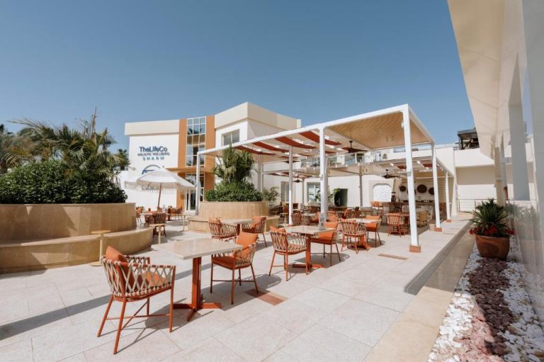 Terraza exterior con mesas y sillas del restaurante TheLifeCo Sharm El Sheikh bajo pérgola blanca