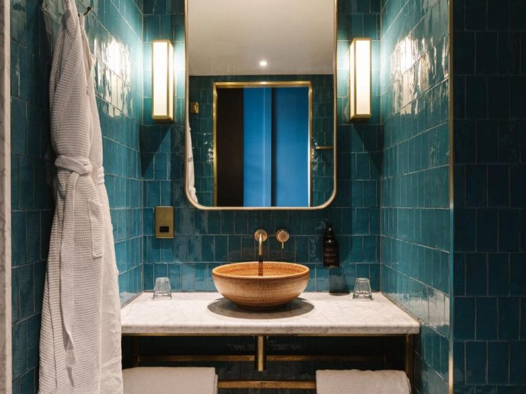 Baño de lujo con azulejos turquesa y lavabo dorado sobre encimera de mármol en The Dean Galway