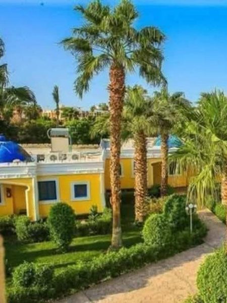 Jardines tropicales con palmeras y fachada amarilla del Mirage Bay Resort & Aqua Park en Egipto