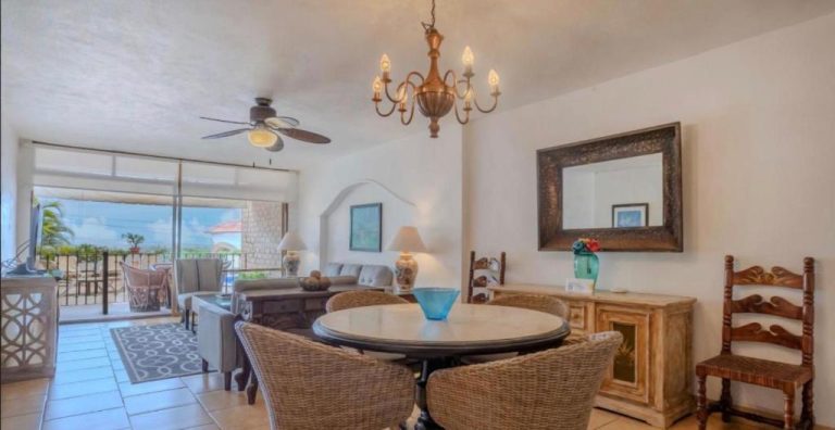 Salón comedor con mesa de ratán y chandelier dorado en Hotel Playa Bonita con vistas a la terraza