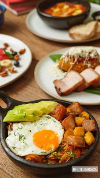 Desayuno completo con huevo frito, aguacate y panceta en sartén de hierro en Hotel Kartaxa