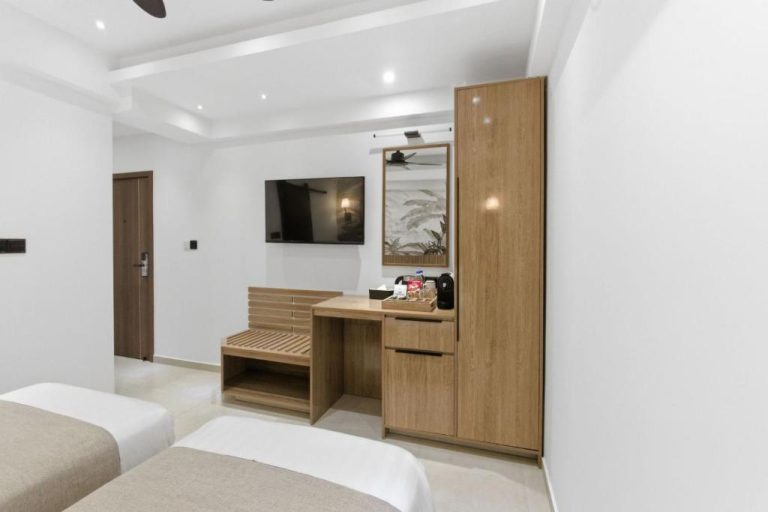 Habitación doble con escritorio de madera, armario y televisión del Hotel Amber Seaside