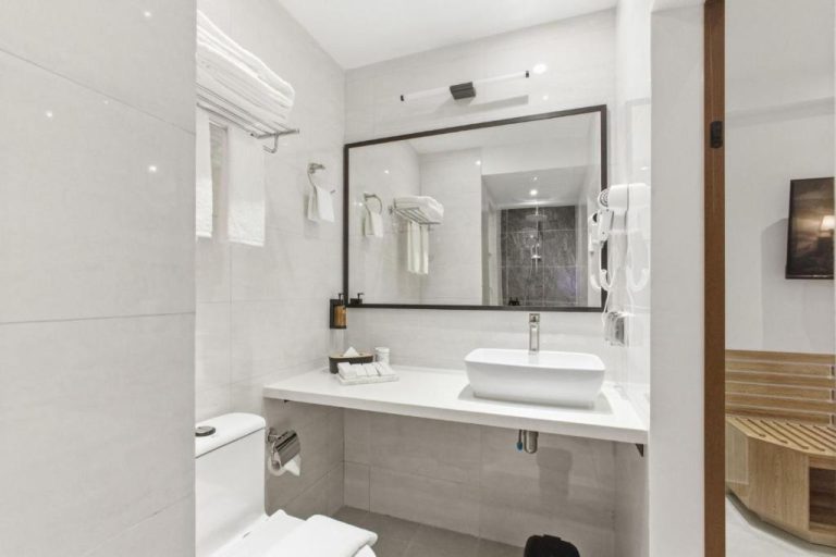 Baño moderno con lavabo sobre encimera blanca y ducha en el Hotel Amber Seaside