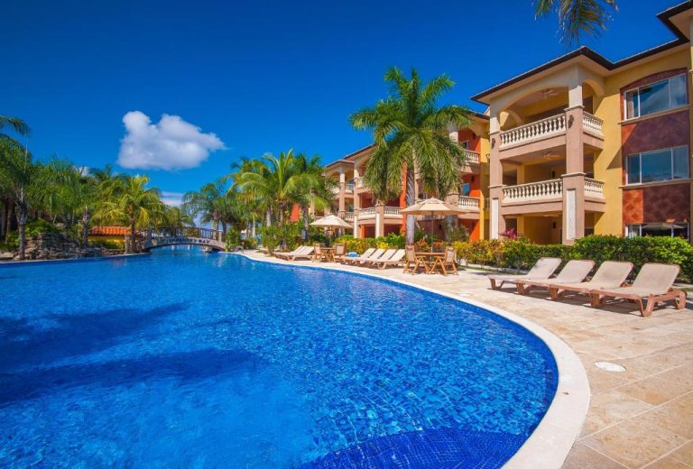 Piscina exterior con tumbonas y palmeras del Infinity Bay Spa & Beach Resort en Honduras