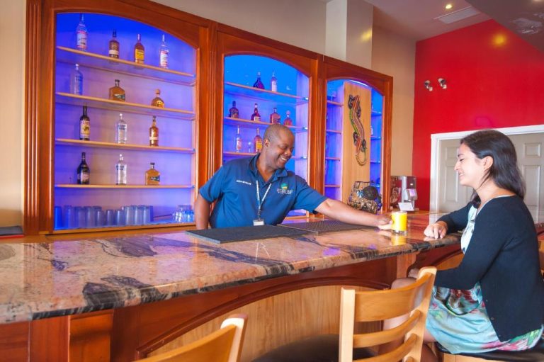 Barman atendiendo a una cliente en el elegante bar interior del Infinity Bay Spa & Beach Resort