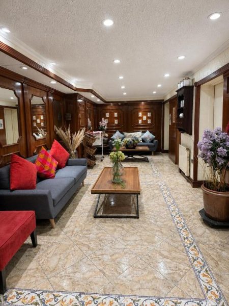Elegante lobby del Hotel Ciudad de Vitoria con sofás, suelo de mármol y paneles de madera