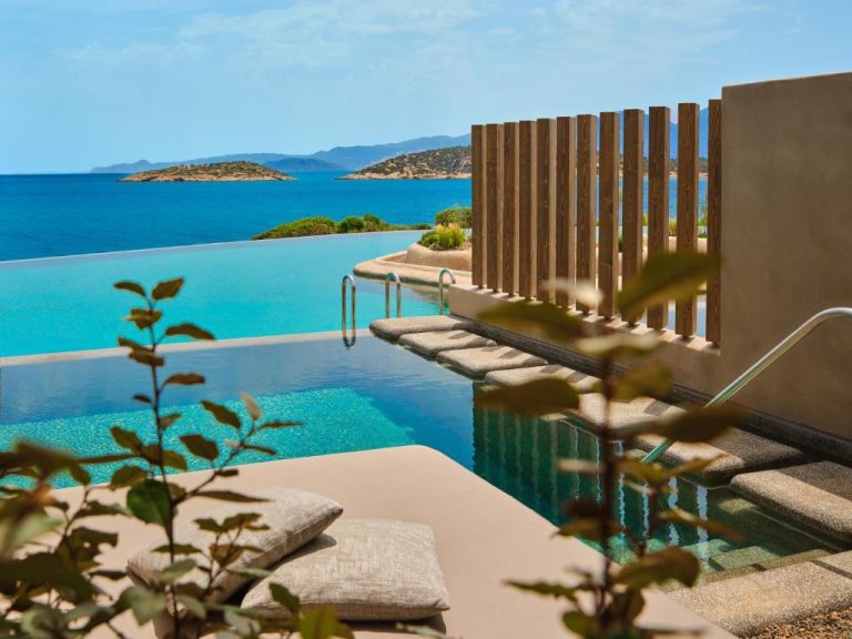Piscina infinita con vistas al mar Egeo y terraza de descanso en Minos Palace Resort Adults Only
