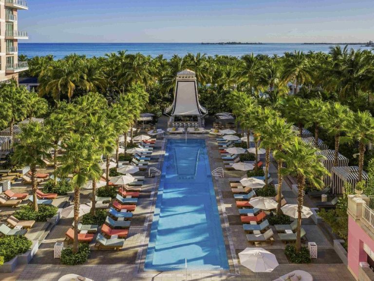 Piscina rectangular exterior con tumbonas y palmeras del SLS Baha Mar con vistas al mar