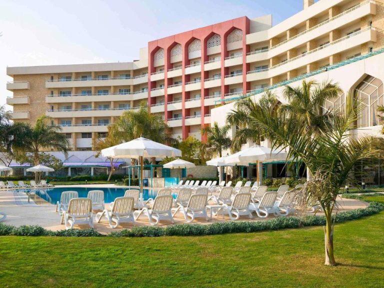 Piscina exterior con tumbonas y sombrillas blancas del Mercure Ismailia Forsan Island