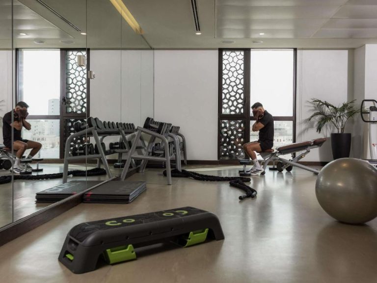 Gimnasio moderno con mancuernas, banco y balón de pilates en Alwadi Hotel Doha MGallery Collection