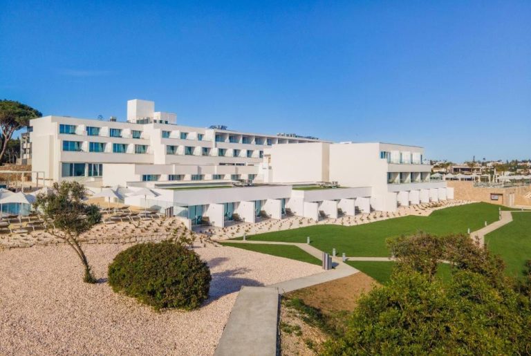 Vista exterior del Wyndham Grand Carvoeiro Algarve con jardines verdes y terrazas privadas frente al mar