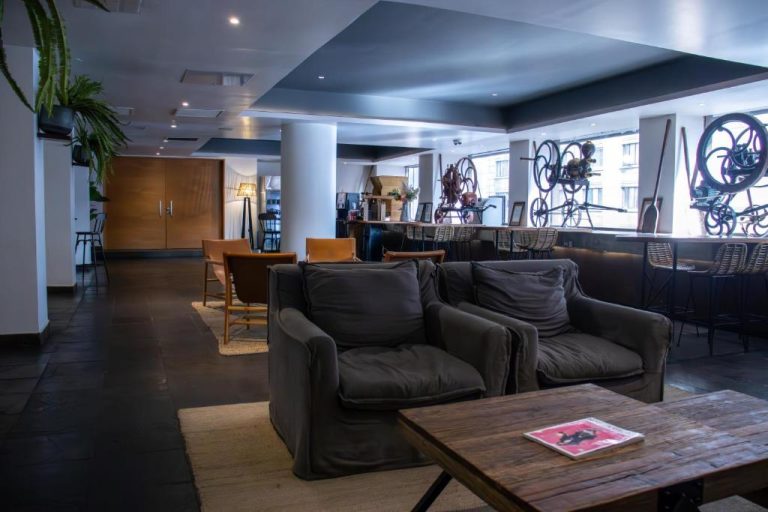 Lobby y zona de descanso del Almacruz Hotel con sofás, mesa de madera y decoración artística