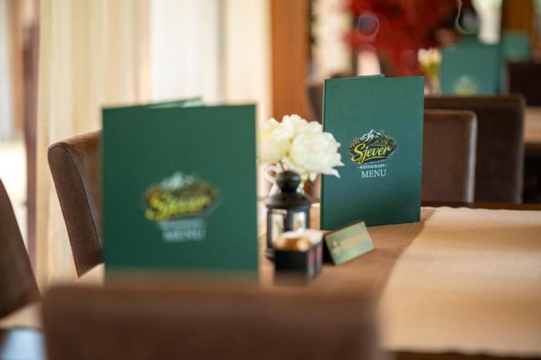 Menús del Restaurante Sjever sobre mesa con flores blancas en el comedor del Hotel Sjever