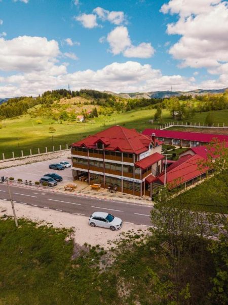 Vista aérea del Hotel Sjever con tejado rojo rodeado de verdes prados y montañas en Bosnia
