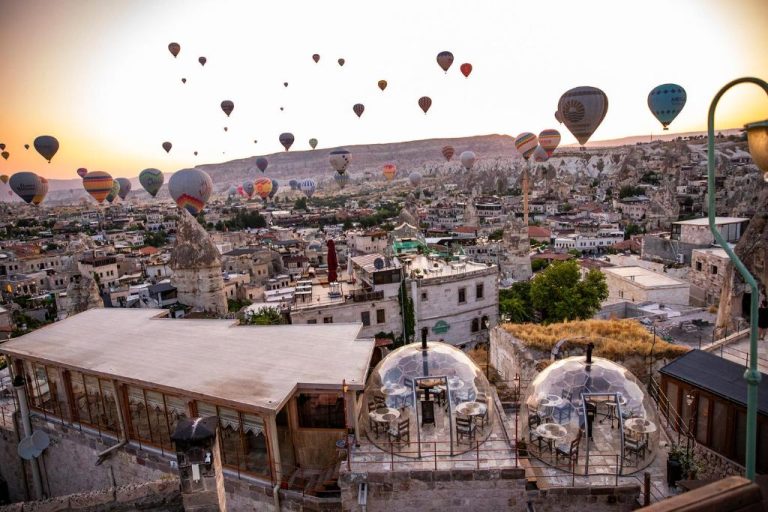Vista panorámica del Charming Cave Hotel en Capadocia con decenas de globos aerostáticos al amanecer