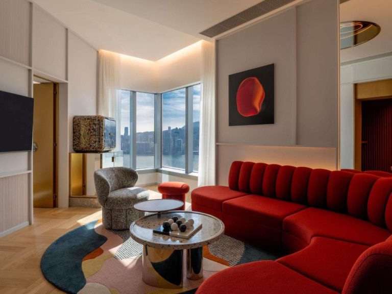 Salón de suite con sofá rojo y vistas a la bahía de Victoria Harbour en Mondrian Hong Kong