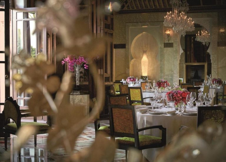 Elegante salón restaurante del Royal Mansour Marrakech con araña de cristal, mesas vestidas y decoración árabe