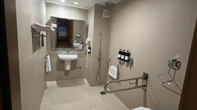 Baño adaptado para personas con movilidad reducida en el Dazzler by Wyndham Asunción con ducha y barras de apoyo