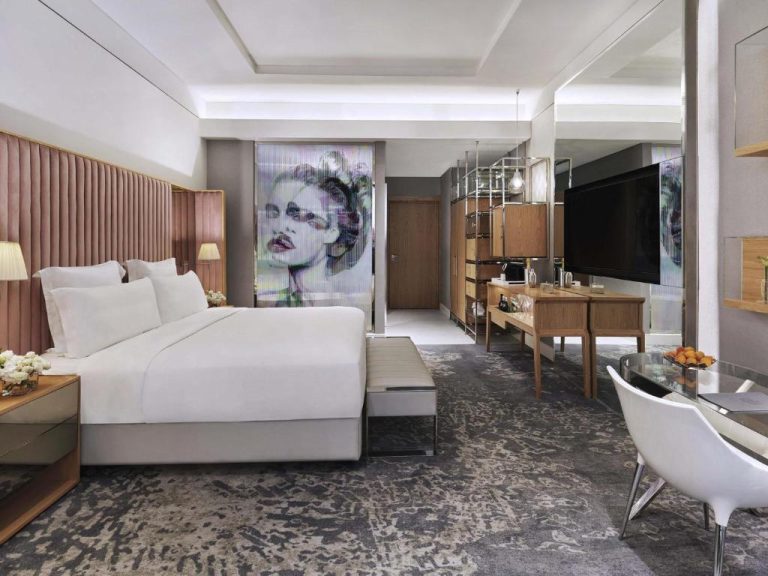 Suite de lujo con cama king, mural artístico y escritorio de madera en SLS Dubai Hotel & Residences
