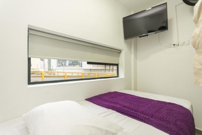 Habitación sencilla con cama, televisor y ventana panorámica en Hotel Zona Express San Diego