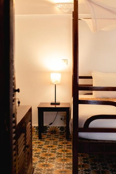 Habitación con cama de dosel de madera y suelo hidráulico en Sambor Village Hotel
