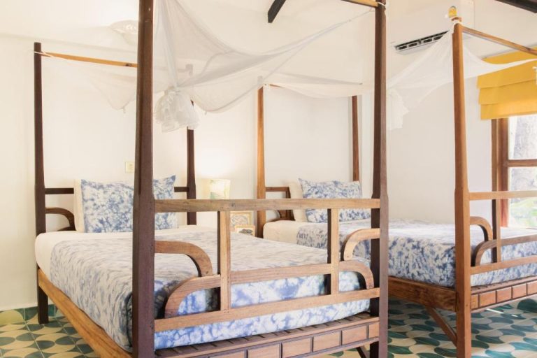 Habitación múltiple con camas de madera y dosel mosquitera en Sambor Village Hotel