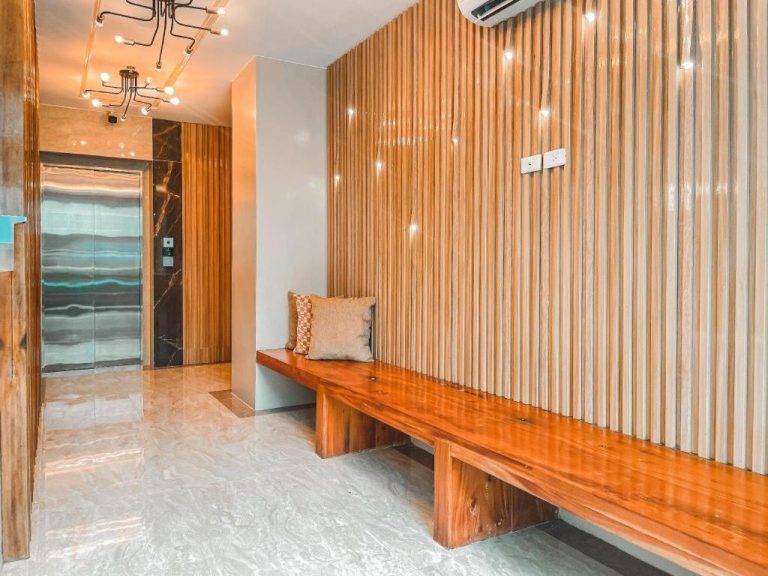 Lobby del Lavero Suites con banco de madera, pared de listones y ascensor de acero inoxidable