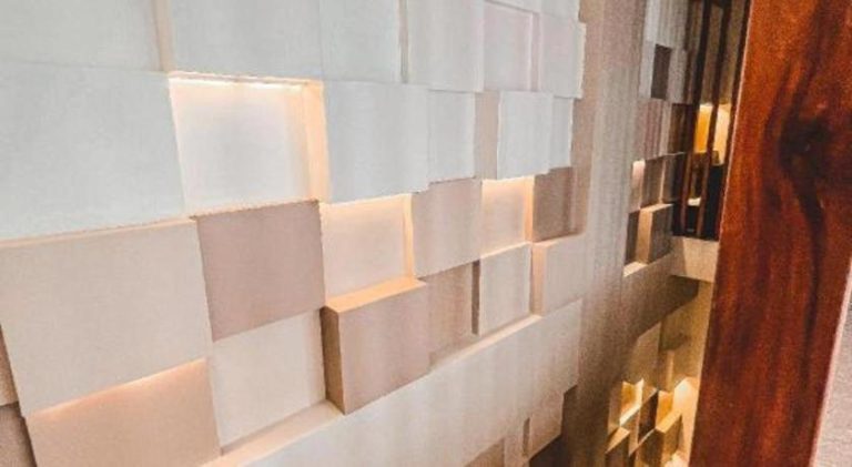 Pared decorativa con paneles 3D blancos e iluminación integrada en el interior de Lavero Suites