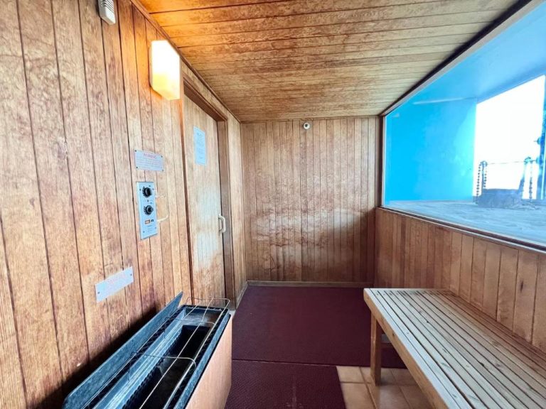 Sauna interior de madera con banco y calentador eléctrico en el Honolulu Hotel