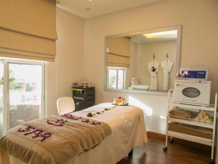 Sala de tratamientos spa con camilla y piedras calientes en Gulf Pearls Hotel