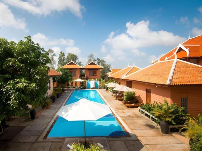 Piscina exterior rectangular con sombrillas y tumbonas del Sambopich Chenla Hotel rodeada de bungalows