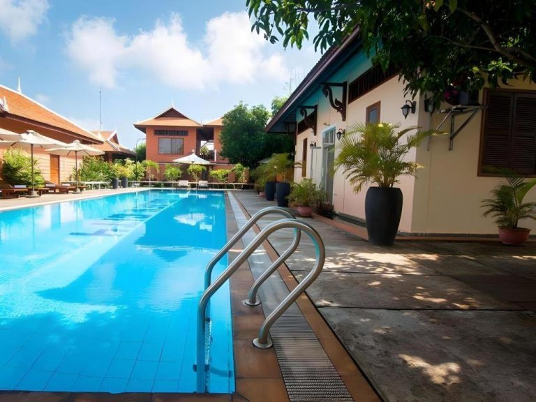Piscina exterior azul con escalerilla del Sambopich Chenla Hotel rodeada de jardines tropicales