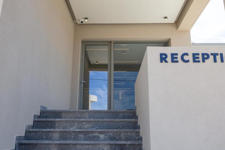 Entrada principal y recepción del Falasarna Bay Hotel con escaleras de mármol y puerta acristalada