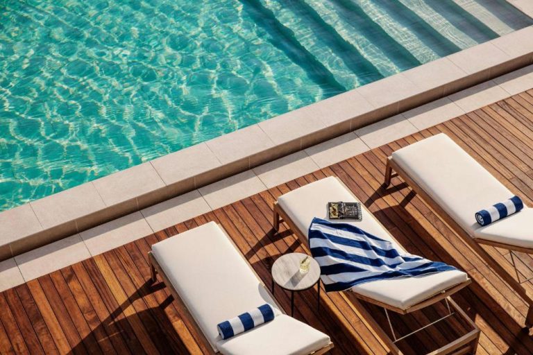 Tumbonas con toallas junto a la piscina exterior del One&Only Portonovi con agua cristalina