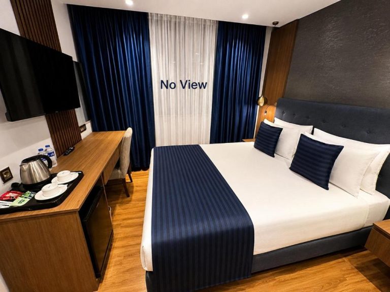 Habitación doble sin vistas con cama king size y decoración en azul marino del The Revia Square Hotel