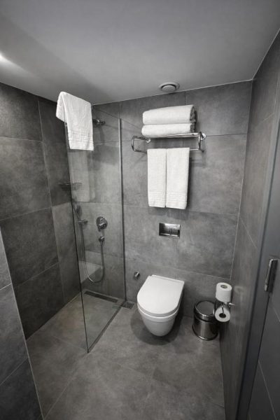Baño moderno con ducha de cristal y sanitario suspendido en The Revia Square Hotel