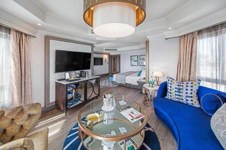 Suite de lujo con sofá azul y sala de estar elegante en Labourdonnais Waterfront Hotel