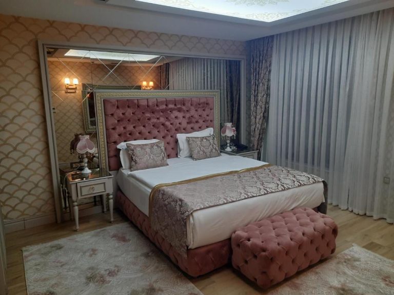 Habitación suite de lujo con cama tapizada en terciopelo rosa en Elysium Green Suites