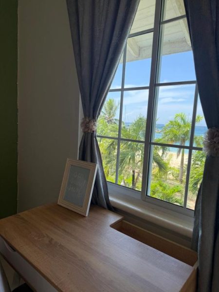Habitación con escritorio y ventana con vistas al mar y palmeras en Ninth River Ocho Rios
