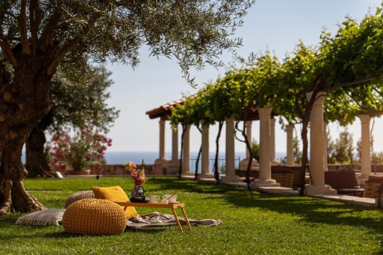 Jardín con olivos y pérgola con columnas del Palace Natali con vistas al mar Mediterráneo