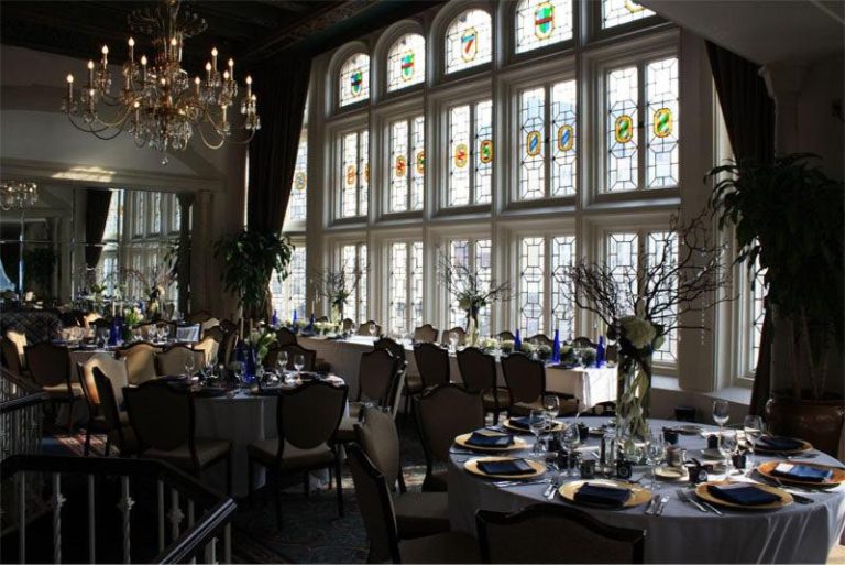 Elegante salón de banquetes del Columbia Club con vitrales y mesas decoradas para evento especial