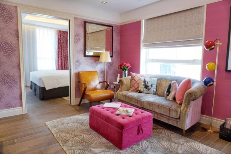 Salón de suite con sofá, paredes rosas y decoración ecléctica en Hotel Madera Hollywood