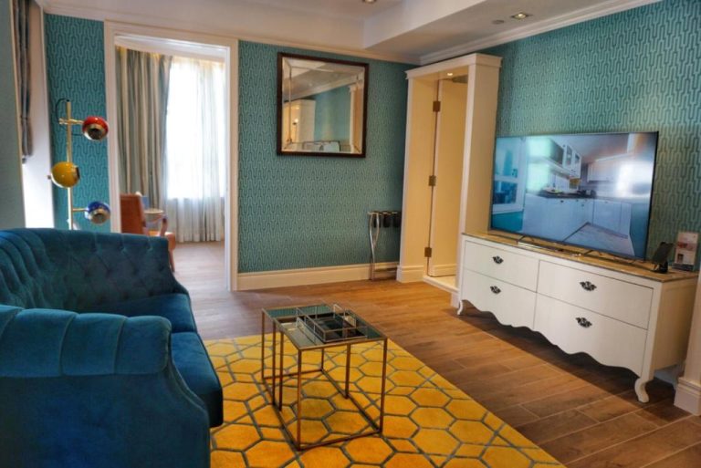 Salón de suite con sofá azul, televisor y decoración vintage en Hotel Madera Hollywood