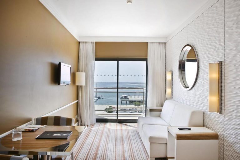 Habitación con sofá blanco y vistas al mar desde el balcón en Real Marina Hotel & Spa