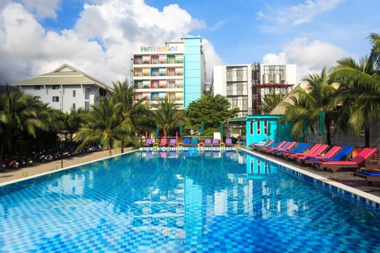 Piscina exterior con tumbonas de colores del Hotel Samui Verticolor rodeada de palmeras