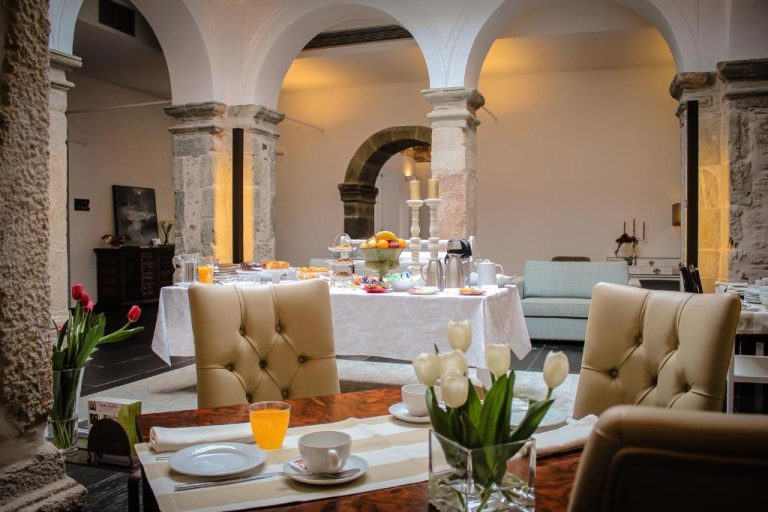 Elegante salón de desayunos con arcos de piedra y mesas preparadas en el Convento Da Serta Hotel